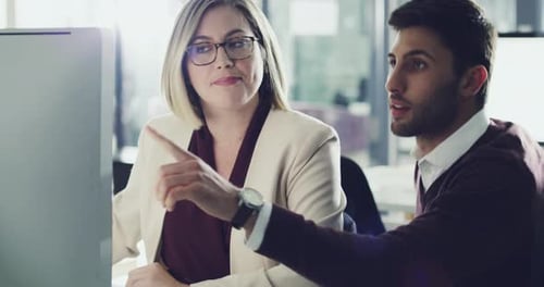 4k footage of two business colleagues brainstorming together behind a computer in the office