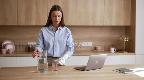 Woman with Robotic Arm Working at Home, Drinking Water