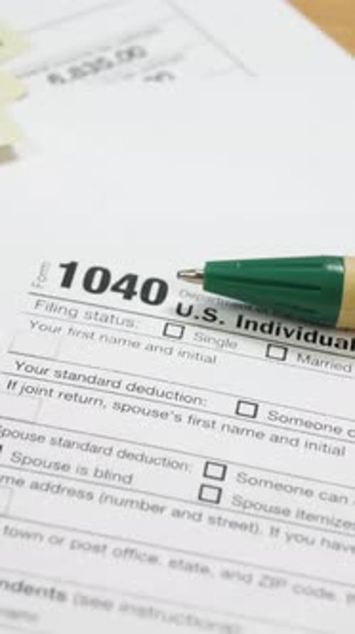 100 Dollar Bills and 1040 Tax Form on Table