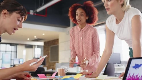 Collaborating on project, diverse women discussing ideas in modern office workspace