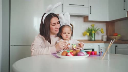 Happy Easter Holiday. Beautiful mother and daughter paint and decorate an egg