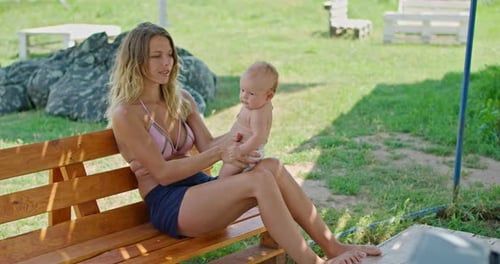 Woman and Baby Sitting on Bench Outdoors