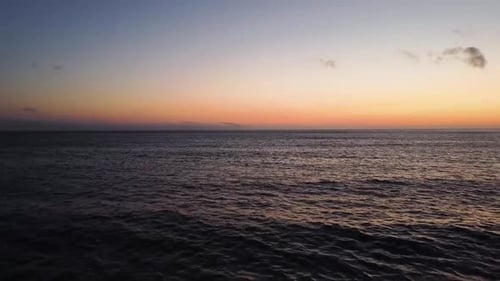Drone shot flying away from the water towards the beach during sunset