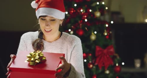 Woman Opens Christmas Present With Delight Indoors