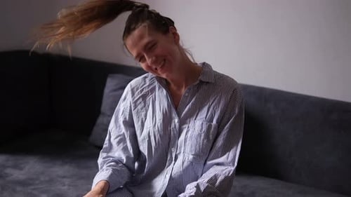 Woman Dancing Joyfully on Couch in Pajamas