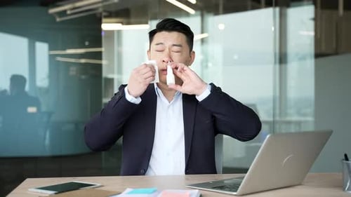 Man in Blazer Uses Nasal Spray at Work