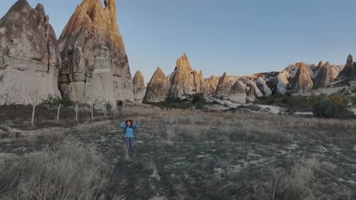 Reisemädchen mit Rucksack und Hut wandert zwischen den Felsen Kappadokiens