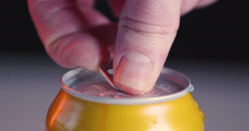 Yellow soda can soft drink with condensed water is opened, close-up, slow-motion