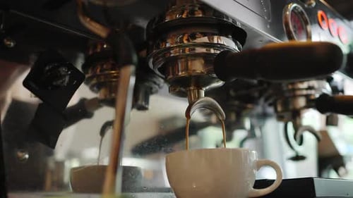 4K Close up of coffee maker machine pouring espresso shot into coffee cup.