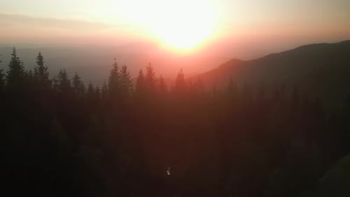 Vidéo aérienne de montagnes à Golden Hour d'un coucher de soleil vibrant avec des nuages ardents qui s'étendent