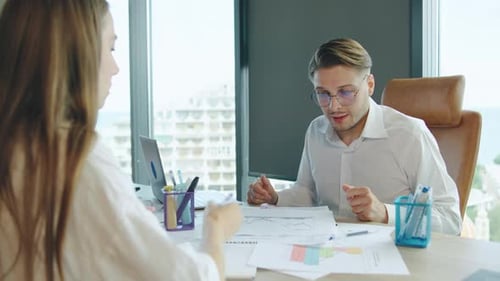 Business Meeting in Modern Office with Two Professionals Discussing Project Details