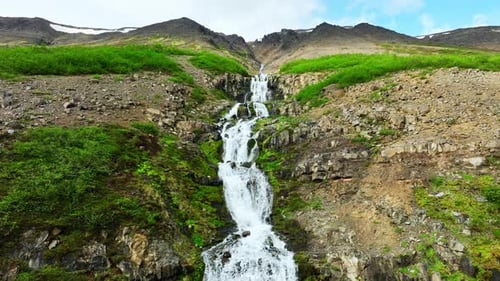 Malerischer Bergwasserfall, der durch eine felsige grüne Landschaft fließt