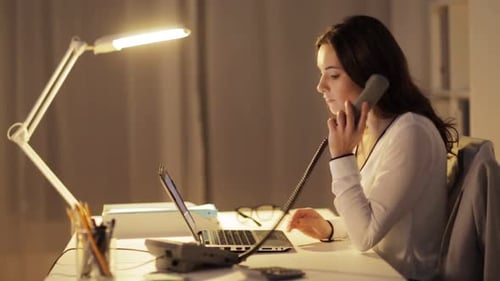 Woman working on laptop computer and answers phone