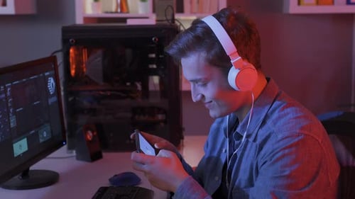 Teenager Playing Game on Phone at Computer