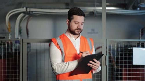 Man With Clipboard Wearing Safety Vest in Workplace