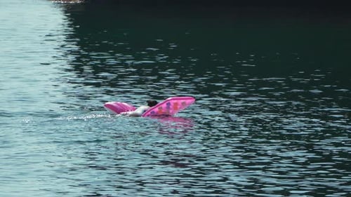 Jovem infantil flutuando na água em uma balsa inflável rosa em mar calmo durante as férias de verão
