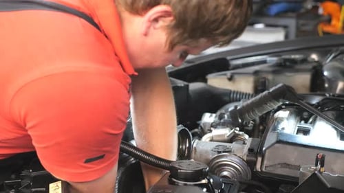 Un mécanicien automobile professionnel travaille sous le capot d'un réparateur de véhicules en réparant le moteur d'une voiture dans un atelier
