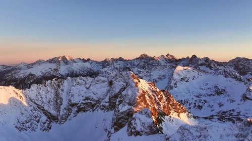 Aerial view of the stunning Alps showcasing snow-covered peaks at sunset