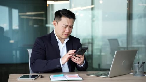 Man Looking Frustrated on Smartphone in Office