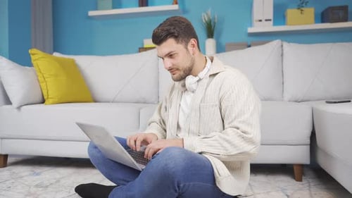 Man Using Laptop Sitting on Floor at Home