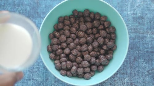 Pouring Milk into Chocolate Cereal in Bowl