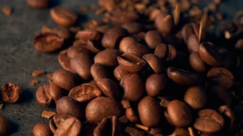 Nahaufnahme: Aromabohnen, gerösteter Kaffee, der schnell auf einen strukturierten dunklen Tisch fällt