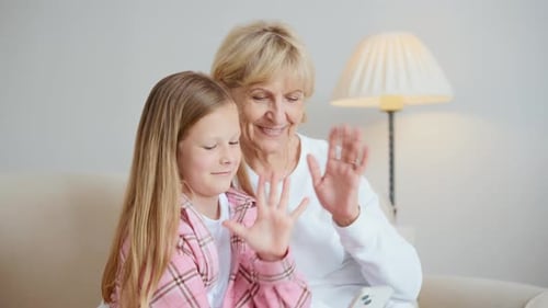 Grandmother and Granddaughter Waving During Video Call on Phone