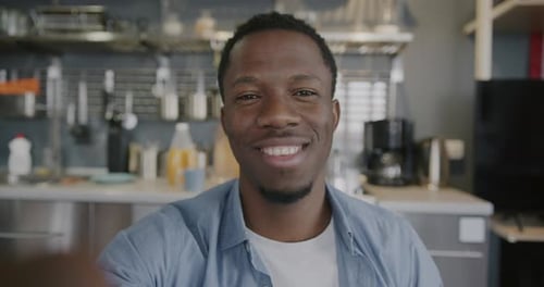 Smiling Young Man Gesturing in Modern Kitchen