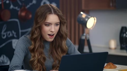 Surprised Woman Getting Good News on Laptop Computer at Home Office. Cheerful