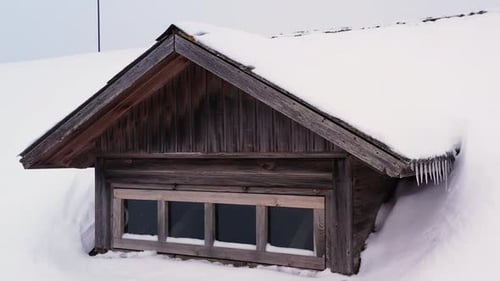 Snow-covered House Roof And Wooden Attic With Icicles In Winter. - aerial