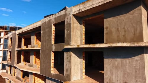 Sunlit exterior of the multi-storied building. Modern houses being built at the construction site.