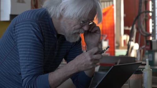 Senior Man Using Laptop In Carpentry Workshop