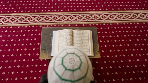 Back view of a lonely Muslim man reciting the Holy Quran in mosque to heal his soul during Ramadan