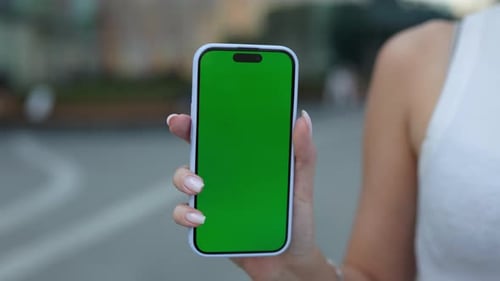 Crop View of Woman Hand Holds Smartphone with Chroma Key Screen in City Setting