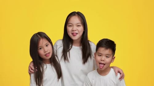 Children Posing Playfully Against a Bright Yellow Background in Resolution