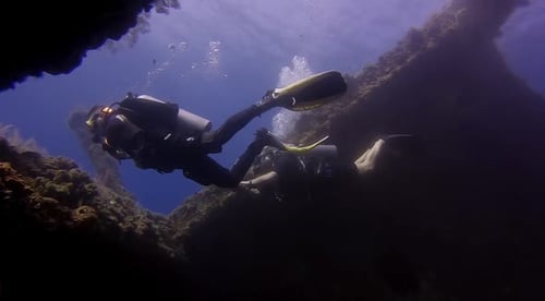 Mergulhadores nadando para fora de um naufrágio