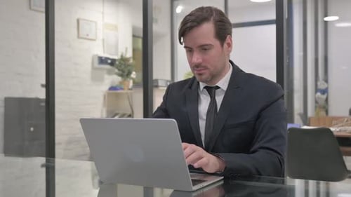 Man in Suit Working at Laptop in Office