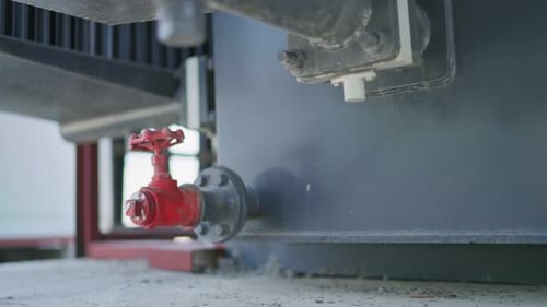 Closeup view of a red gate valve attached to a industrial equipment.