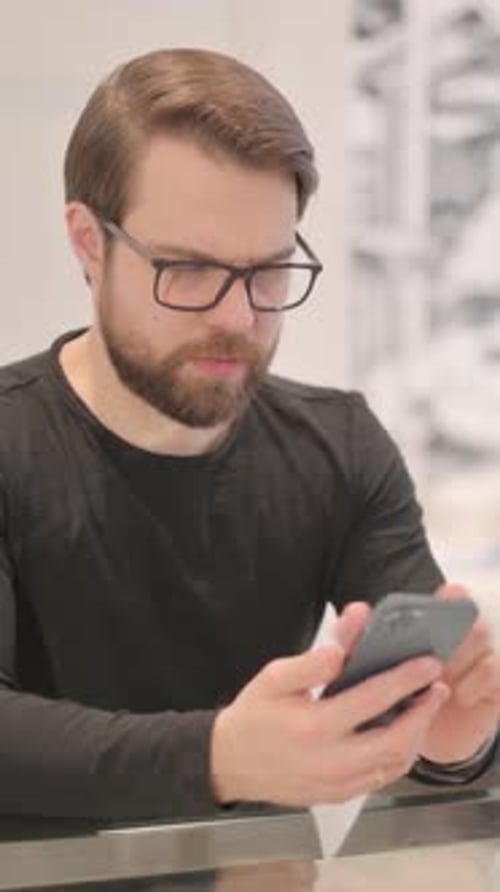 Man with glasses using mobile smartphone close up