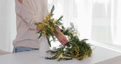 Woman Arranging Yellow Flowers in White Ceramic Boot