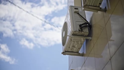 Outdoor Wallmounted HVAC Condenser Unit on Modern Building Facade Under Blue Sky Showing Cooling