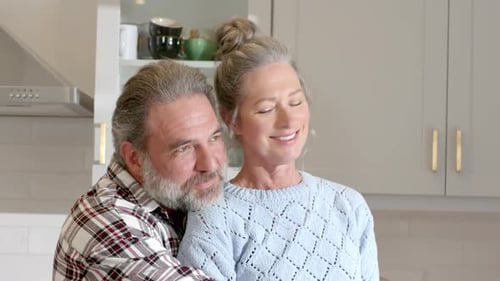 Mature Couple Embracing in Bright Kitchen