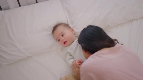Loving Mother Playing with her Happy Baby on Bed