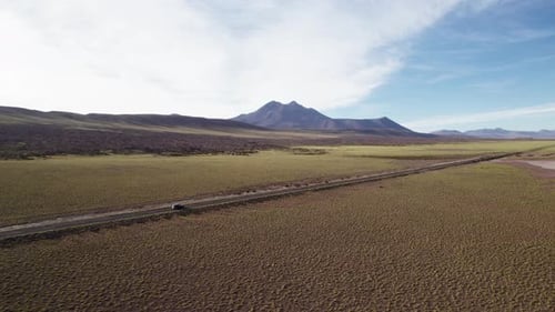 Long Desert Road Leading Towards Distant Mountains Under a Blue Sky