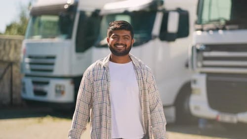 Smiling man stands in front of trucks