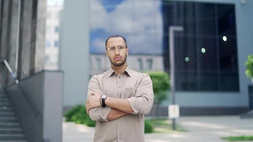 Serious Young Man with Arms Crossed Outdoors