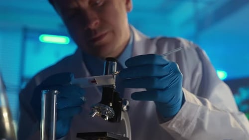 Scientist Analyzing Sample on Microscope in Bright Lab
