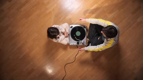 Overhead view of young adults listening to record