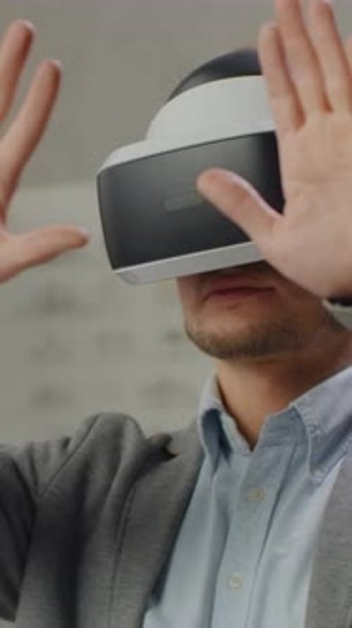 Man Adjusting His Indoor Vr Headset with a Neutral Focused Expression in a Light Blue Shirt and Gray
