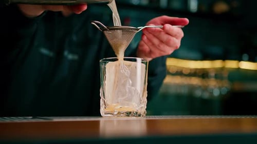 Bartender Pouring Cocktail into Glass with Ice
